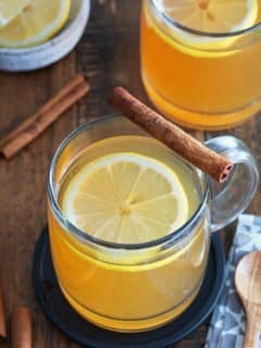 A bourbon hot toddy garnished with a lemon slice and a cinnamon stick.