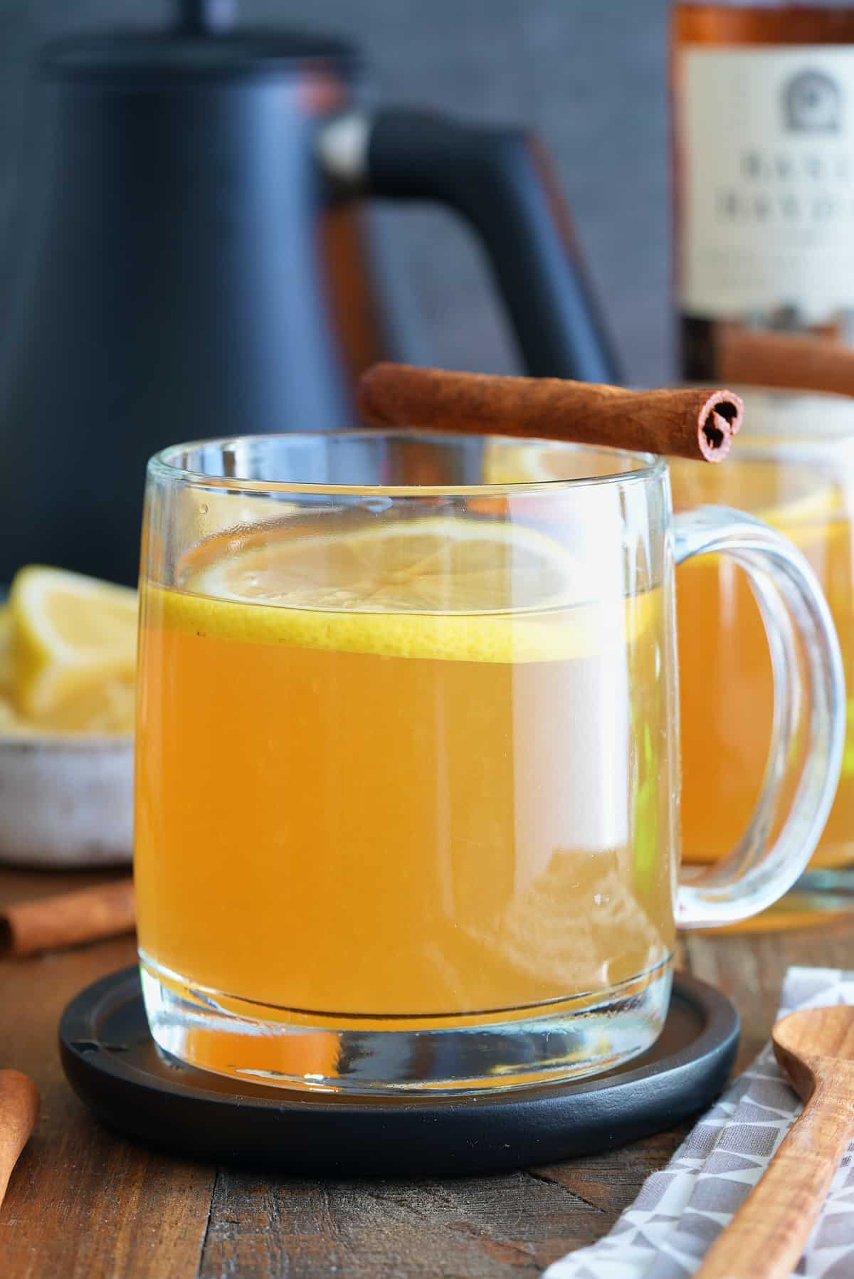 A bourbon hot toddy garnished with a lemon slice and a cinnamon stick.