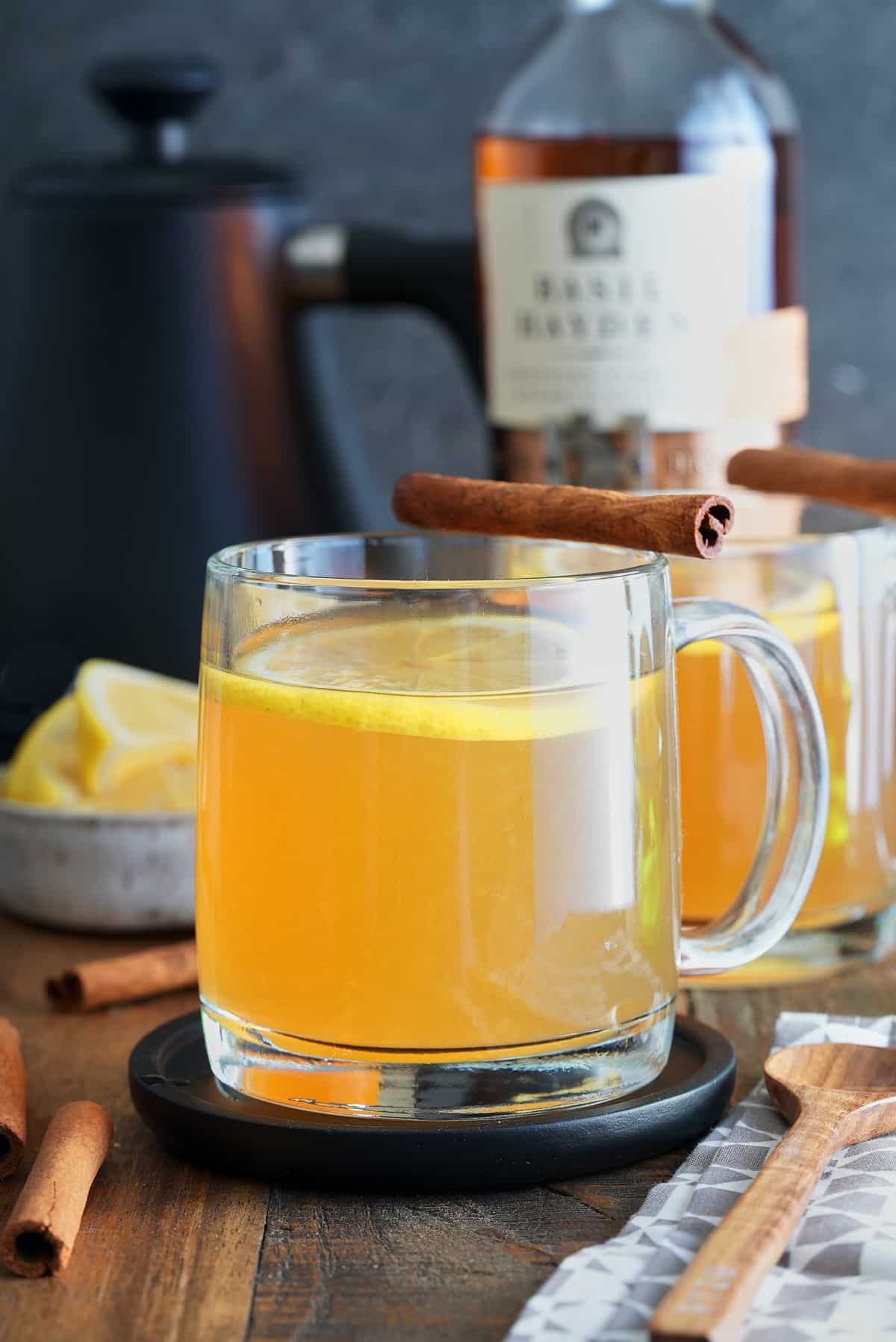 A bourbon hot toddy garnished with a lemon slice and a cinnamon stick.