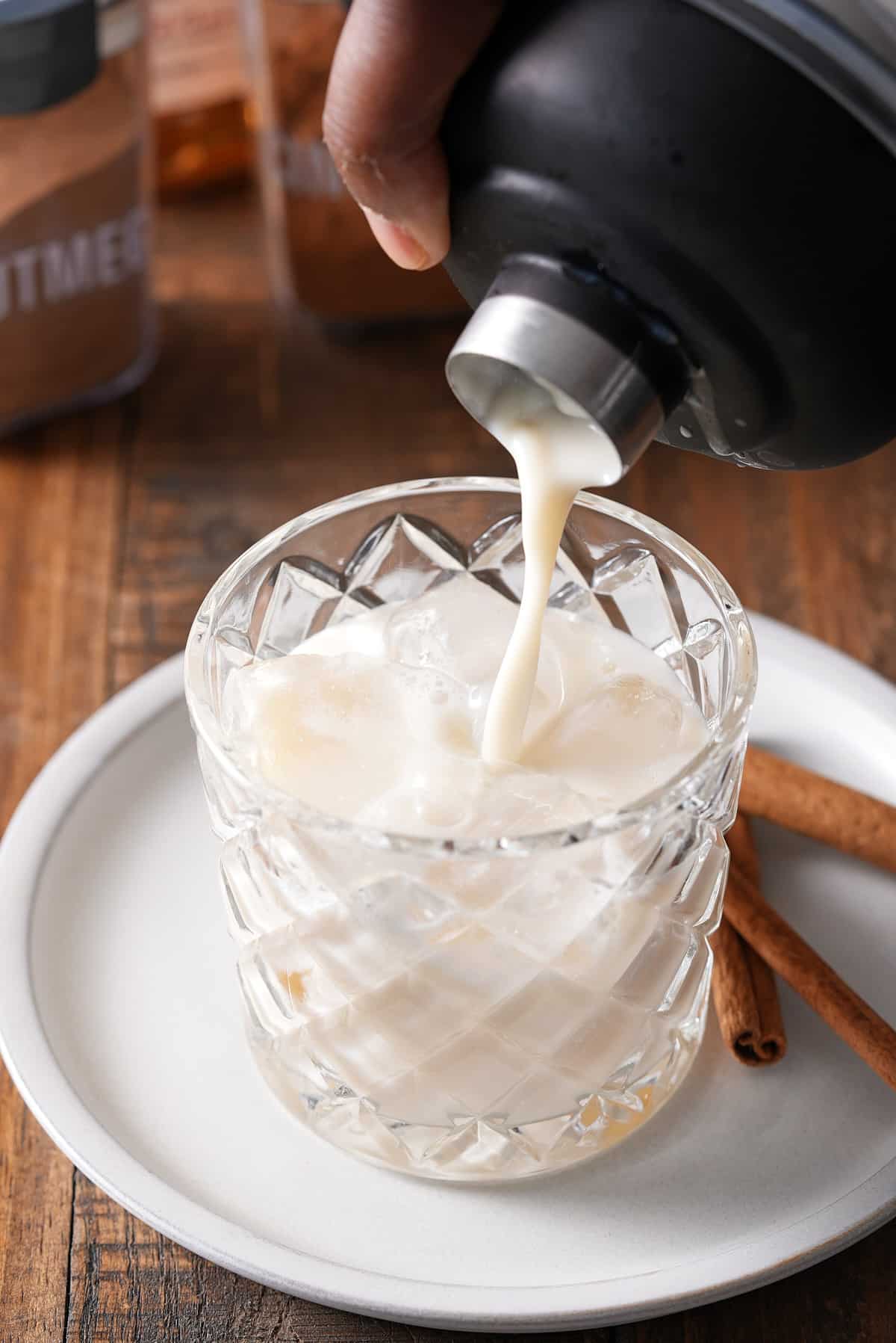 bourbon milk punch being poured over ice.