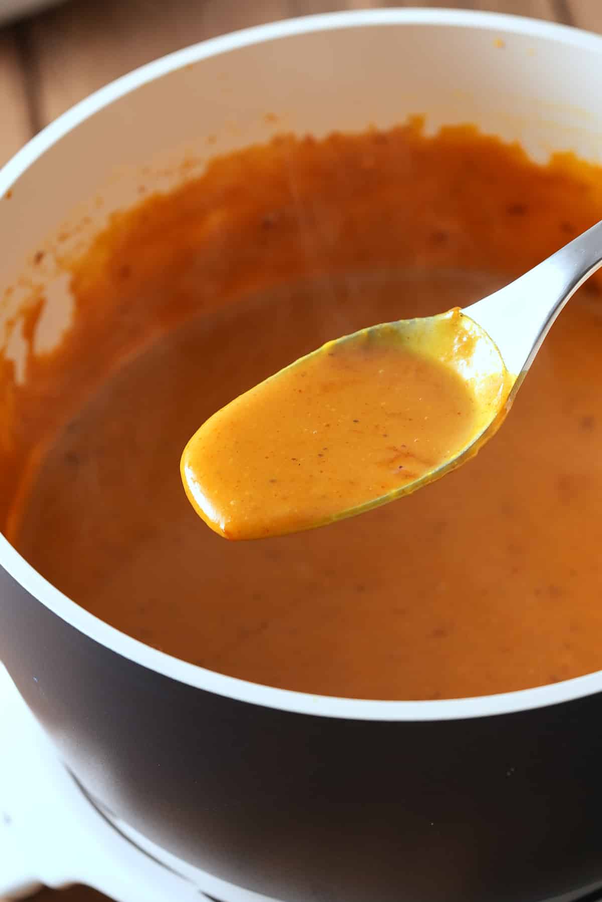 A saucepan of BBQ sauce with a spoon of the sauce.