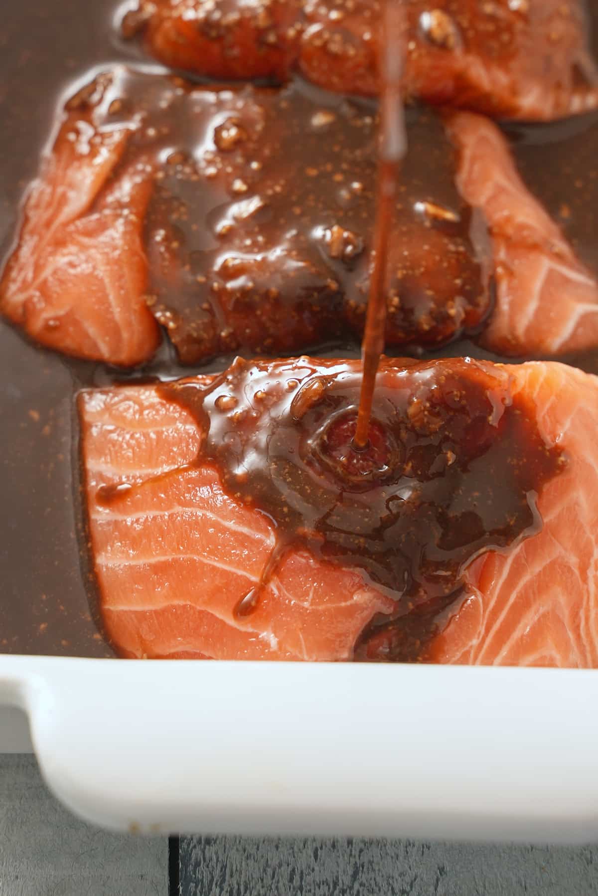 Marinade being poured over salmon.