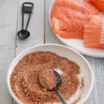 A bowl of salmon seasoning with a plate of raw salmon filets set alongside.
