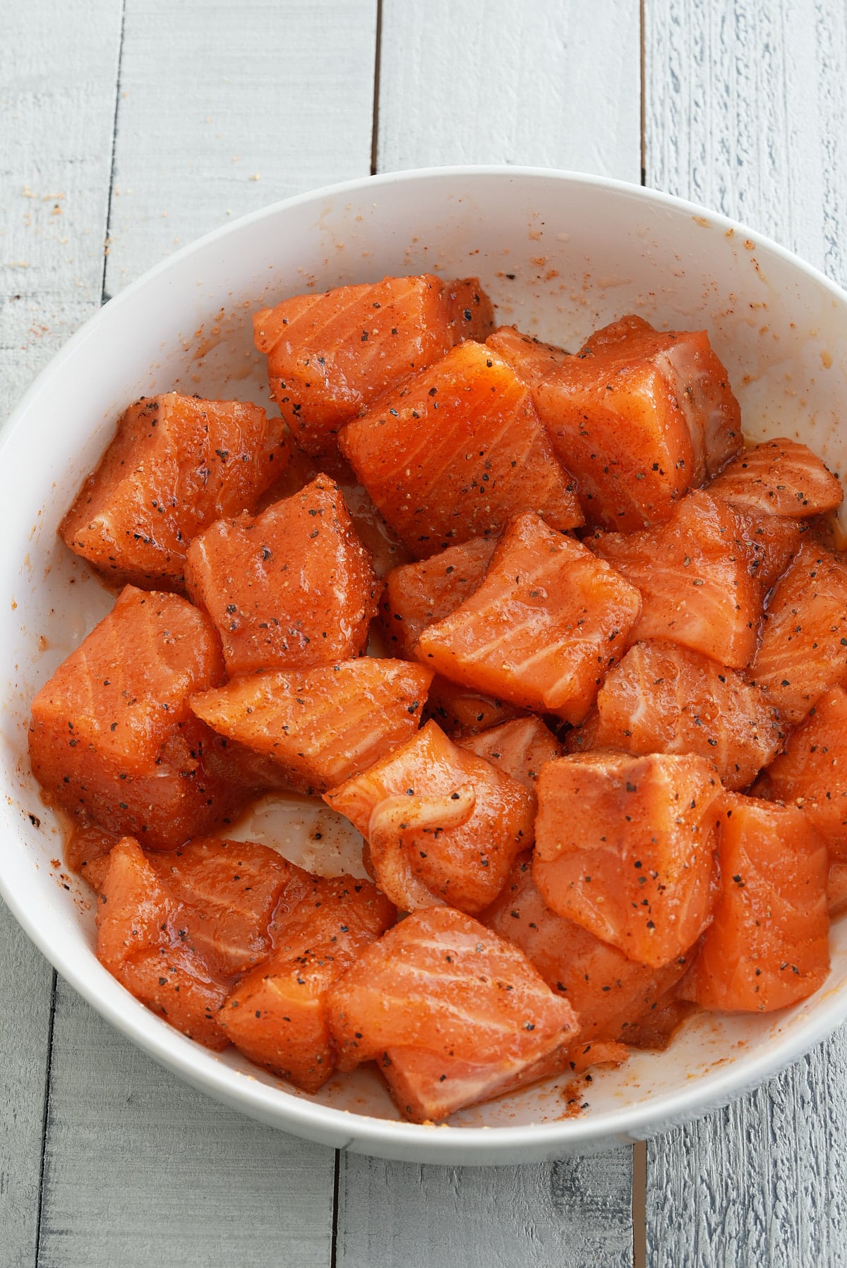 Cubes or raw salmon coated in salmon seasoning and oil.