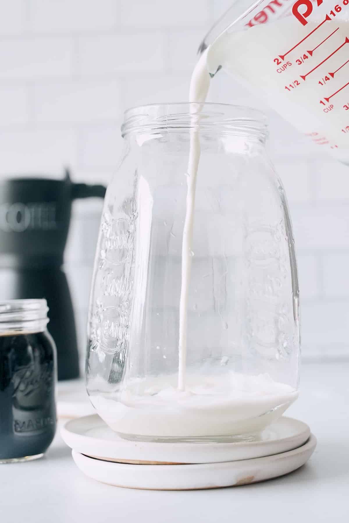 Pouring cream into a large glass container.