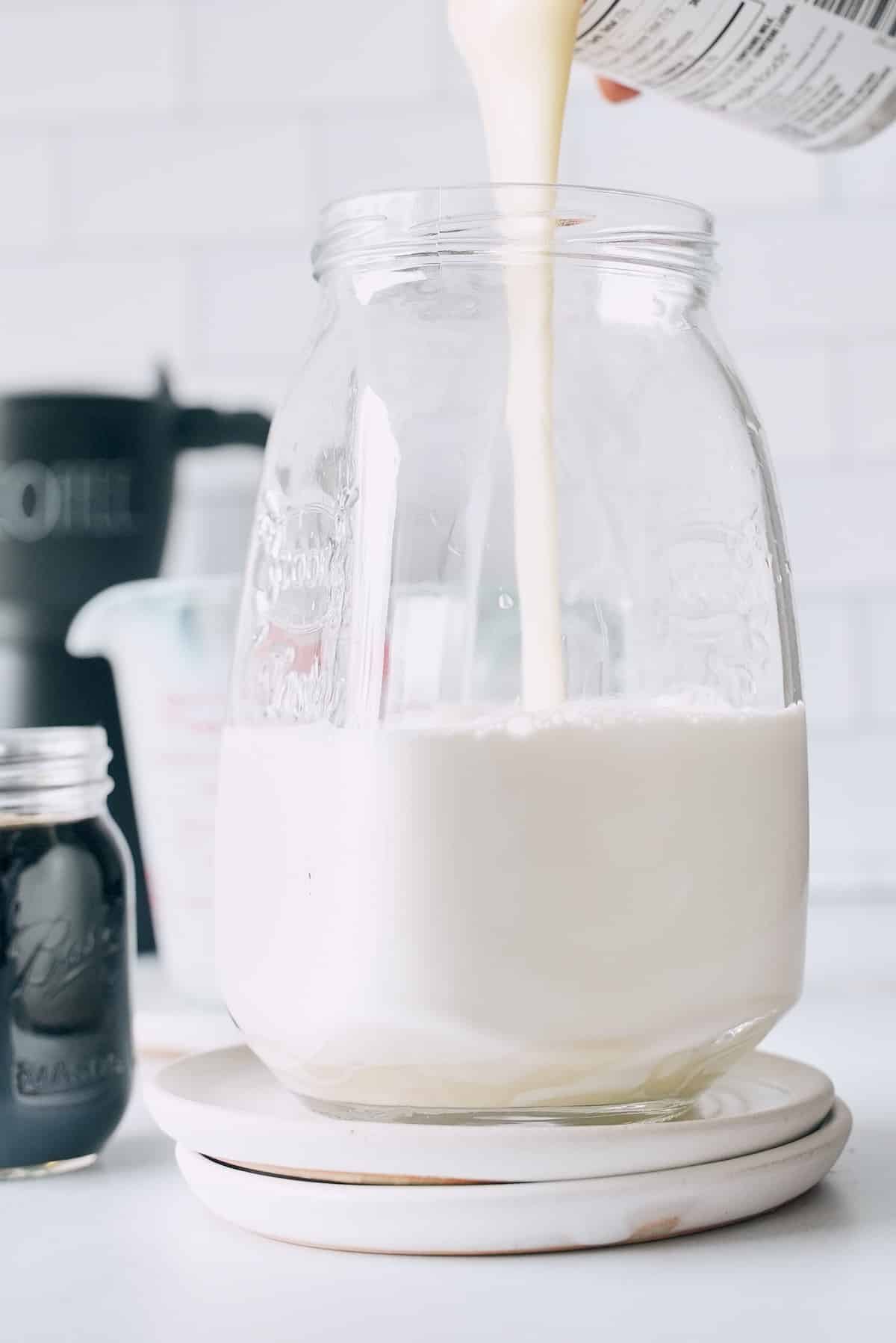 Pouring condensed milk into a tall glass.