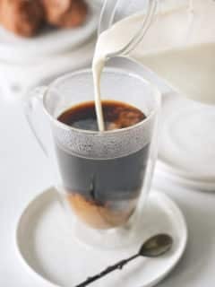 Pouring coffee creamer into fresh coffee.