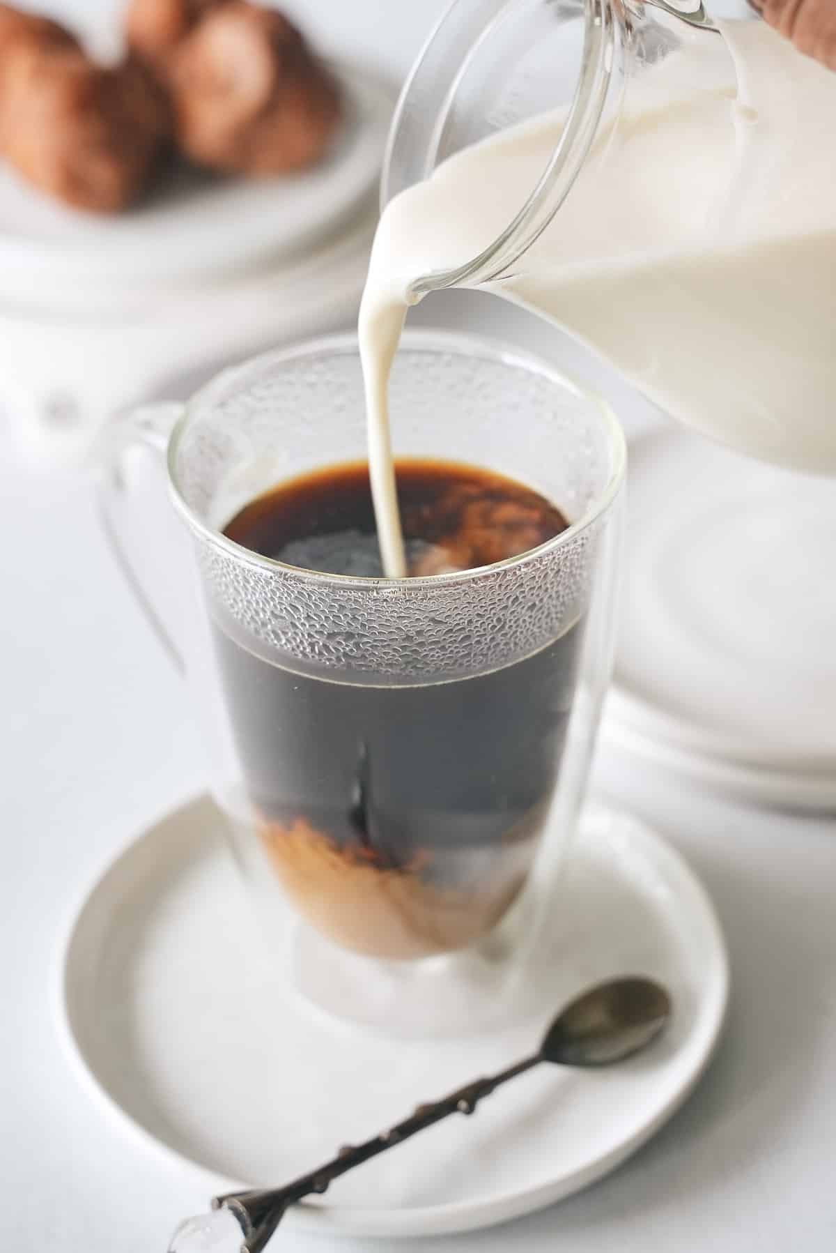 Pouring coffee creamer into fresh coffee.