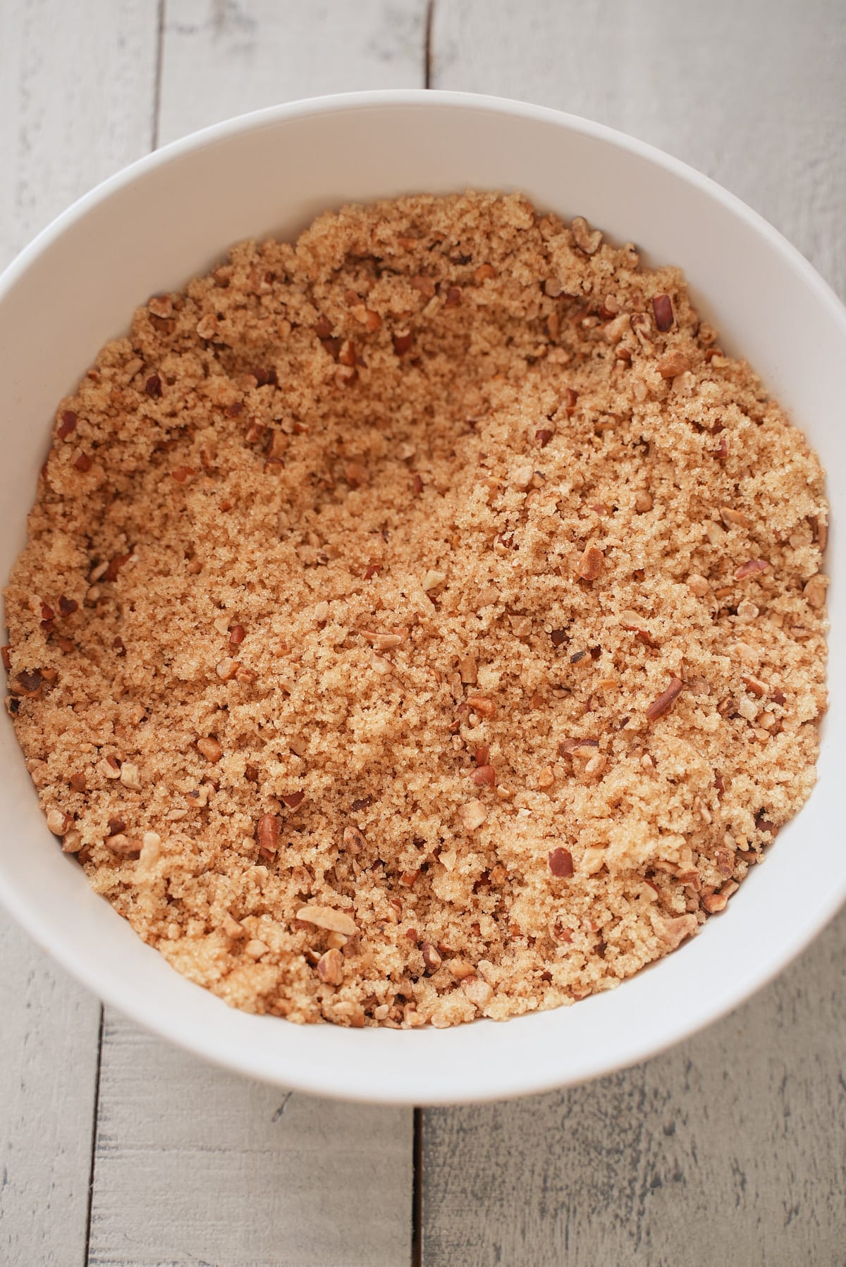 White bowl filled with combination of brown sugar, chopped pecans and ground cinnamon.