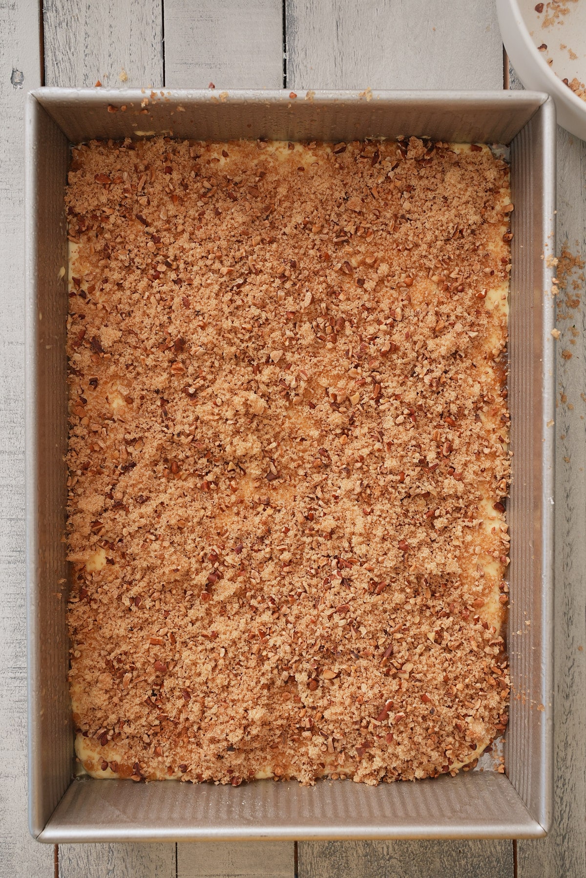 Brown sugar and pecan crumb mixture spread over cake mix in a rectangular cake tin.