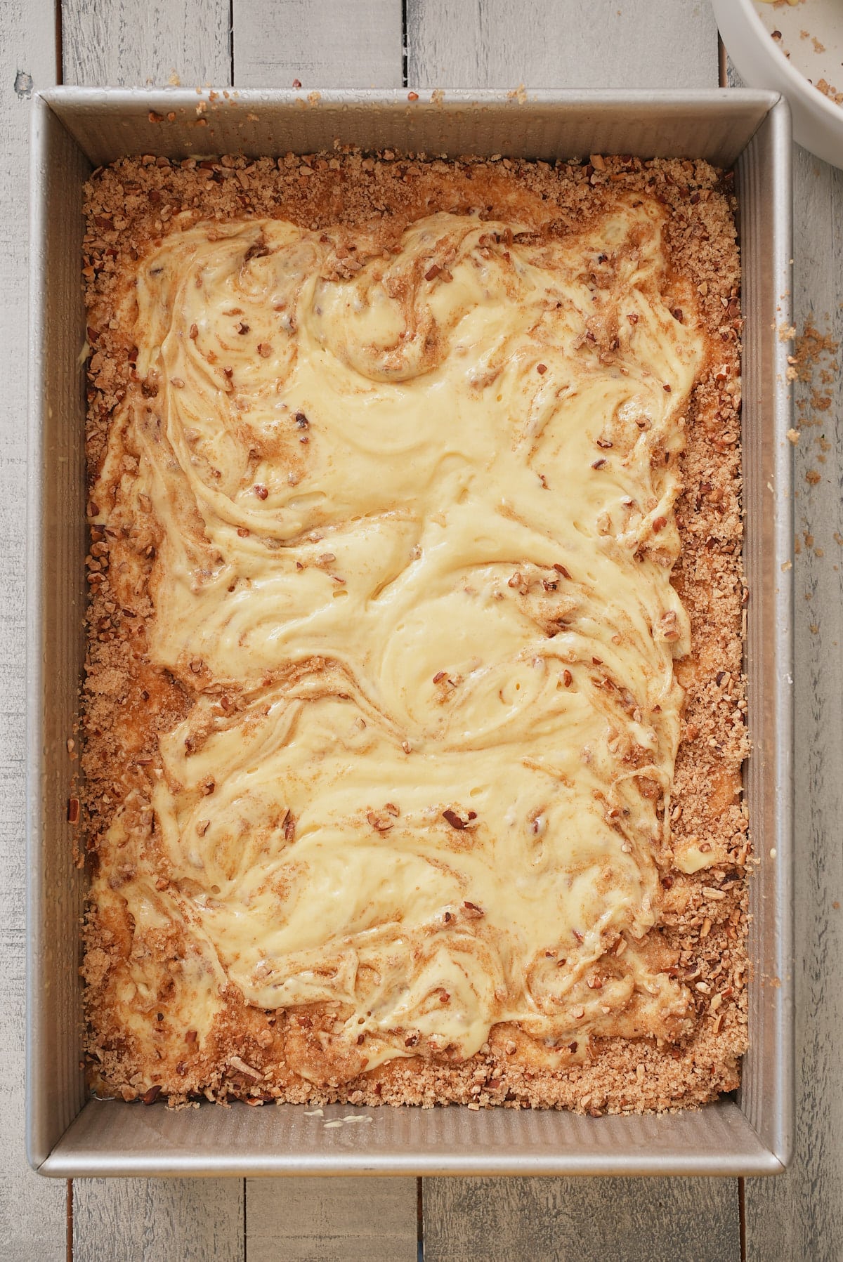 Cake mix batter and sugar and pecan crumb mixture swirled together in cake tin to form a marble effect.