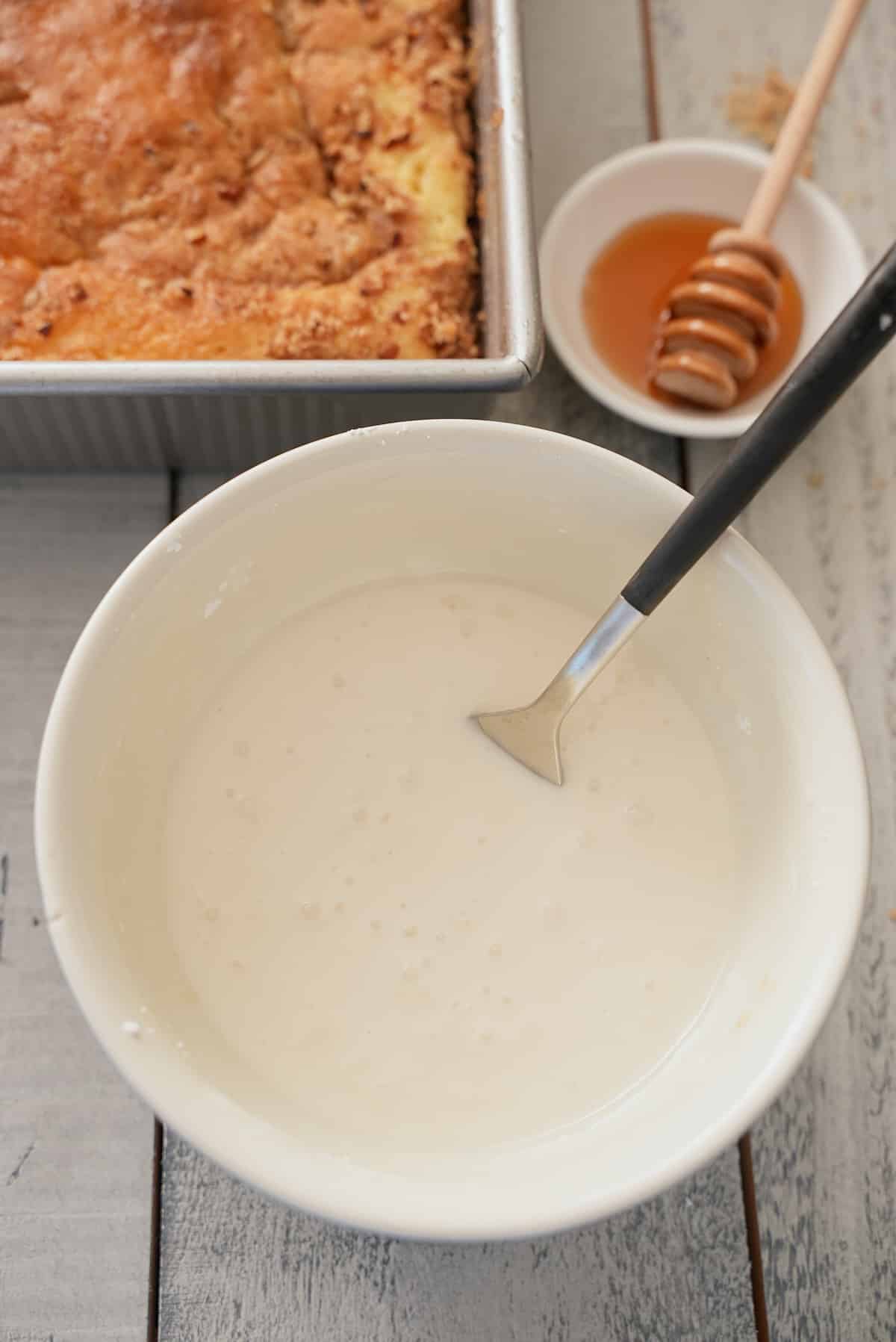 A white bowl filled with vanilla and honey sugar glaze.