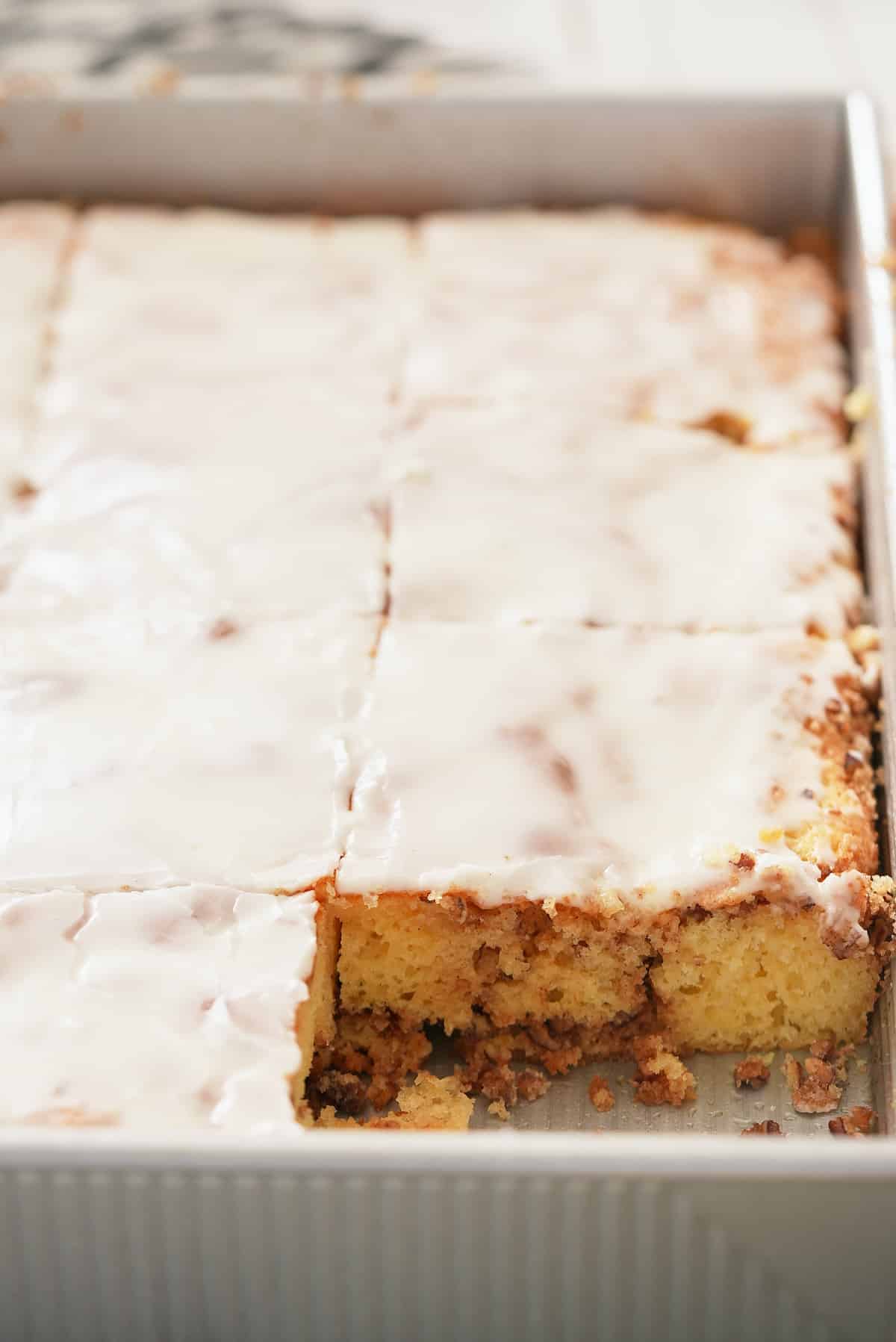 A rectangular cake tin filled with honey bun cake with a slice removed.