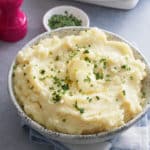 A bowl of microwave mashed potatoes topped with butter and garnished with freshly chopped chives.