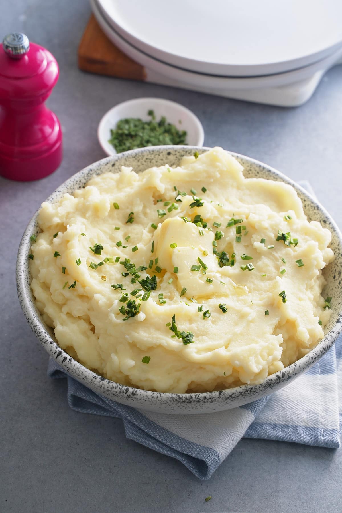 A bowl of microwave mashed potatoes topped with butter and garnished with freshly chopped chives.