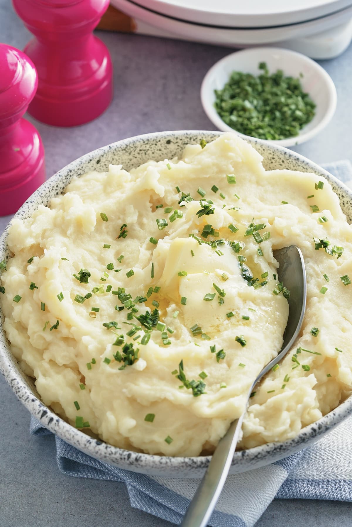 A bowl of microwave mashed potatoes topped with butter and garnished with freshly chopped chives.