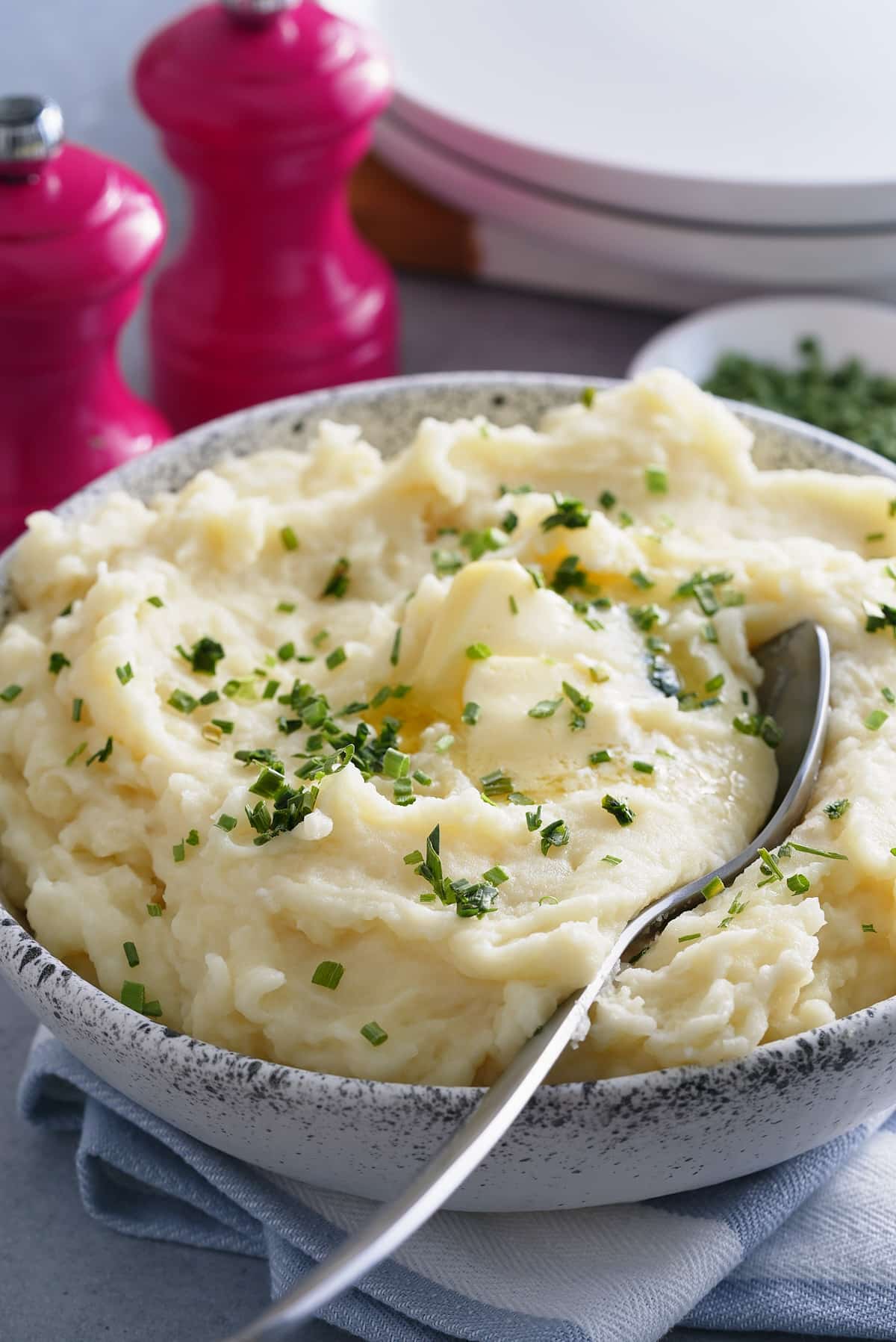 A bowl of microwave mashed potatoes topped with butter and garnished with freshly chopped chives.