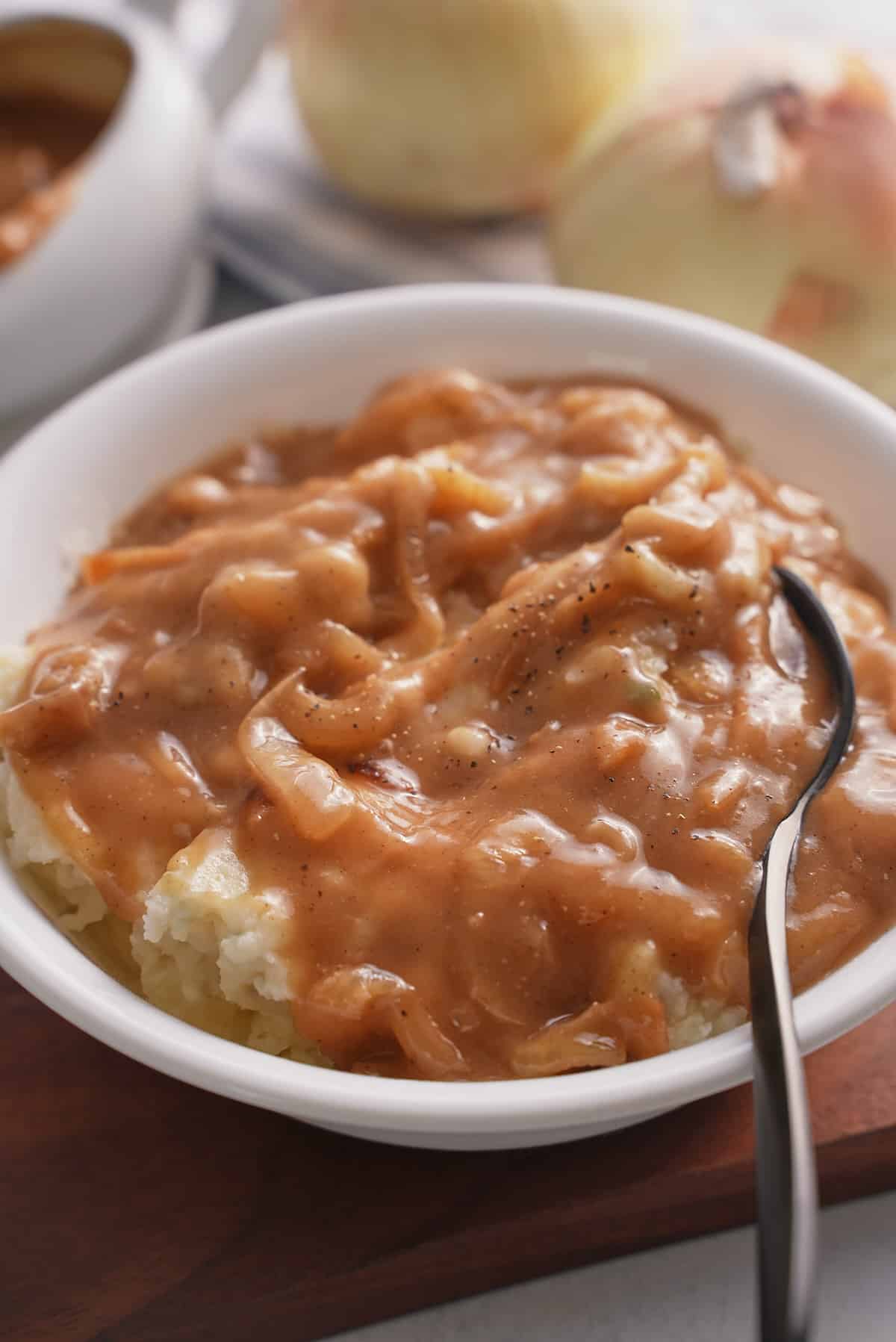 A white bowl of mashed potatoes topped with onion gravy.