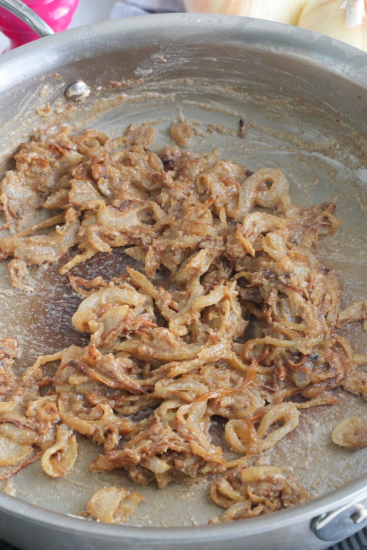 A large skillet of cooked onions coated in flour.