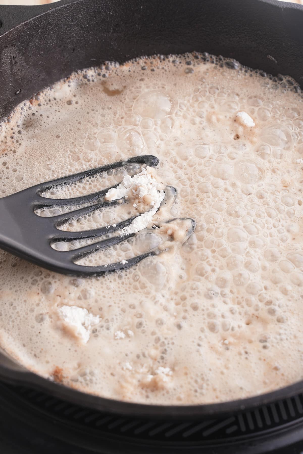 Using a whisk to make a roux with the flour.