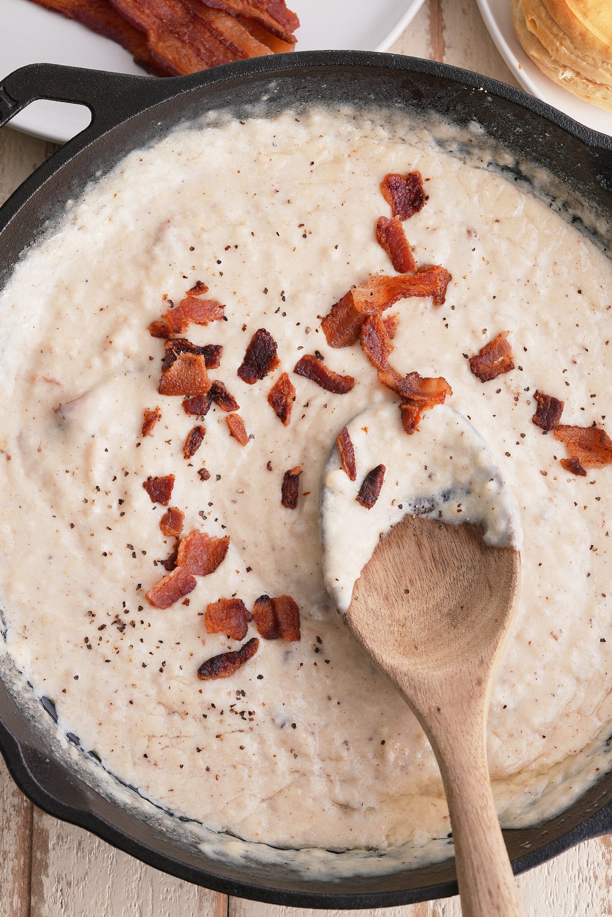 Stirring the gravy with a wooden spoon.