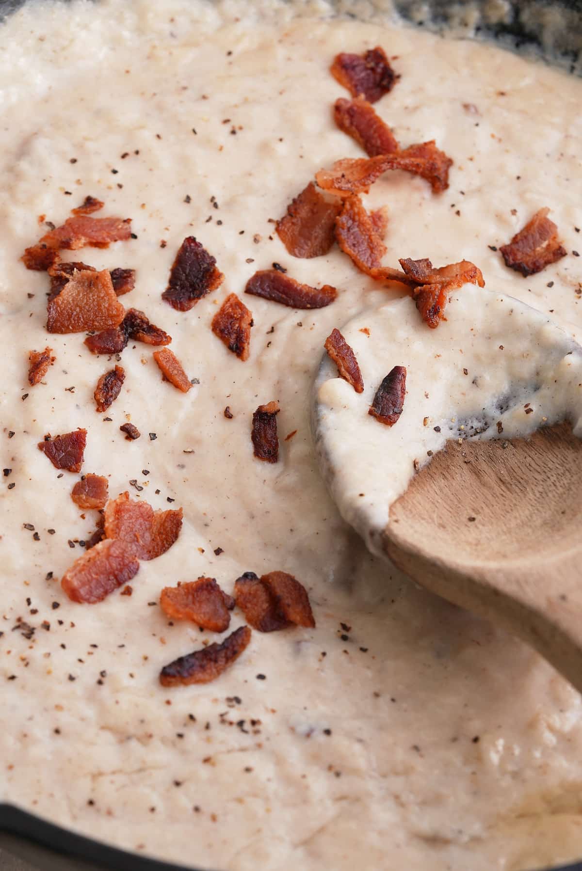 Stirring the bacon gravy with a wooden spoon.