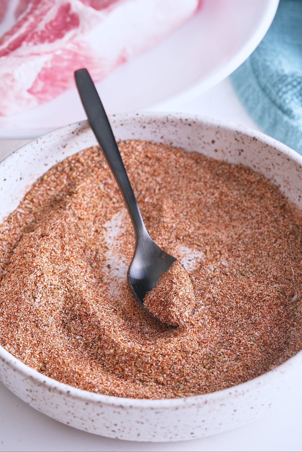 Mixed pork chop seasoning in a white bowl with a spoon.