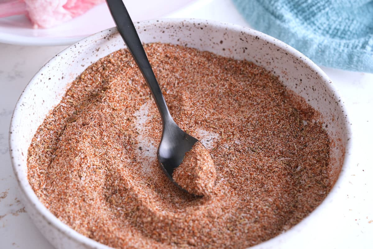 Mixed pork chop seasoning in a white bowl with a spoon.