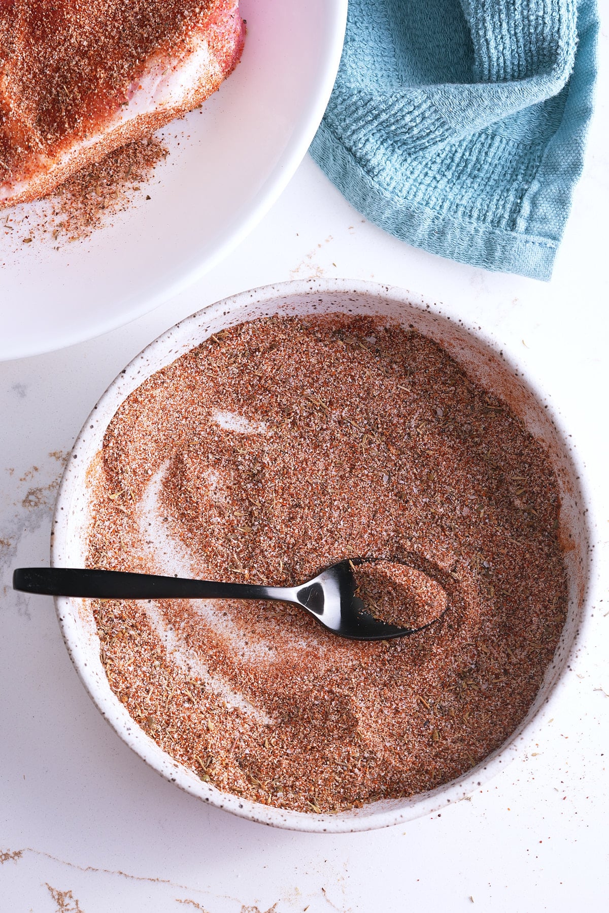 Mixed pork chop seasoning in a white bowl with a spoon.