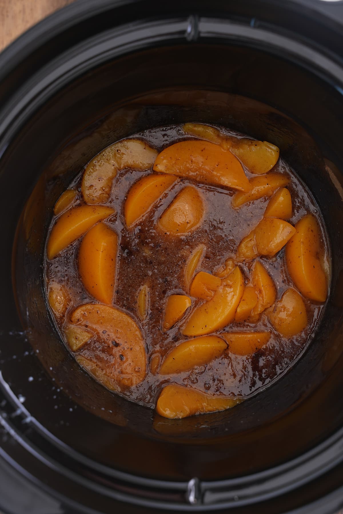 Peaches placed in the bottom of the slow cooker.
