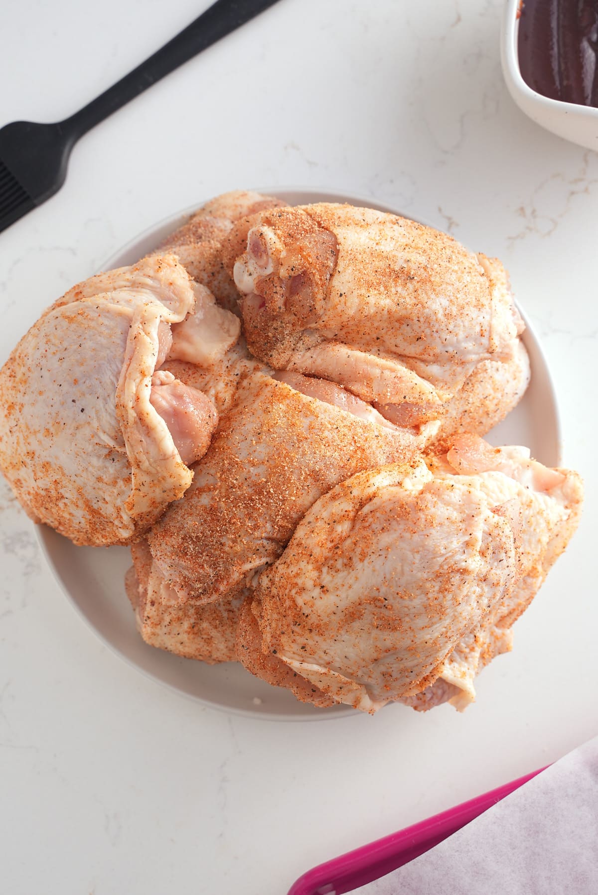 Seasoned chicken thighs on a plate.