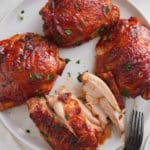 baked bbq chicken thighs being eaten from a plate.