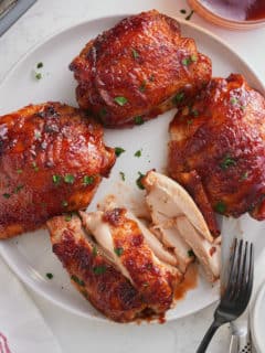 baked bbq chicken thighs being eaten from a plate.