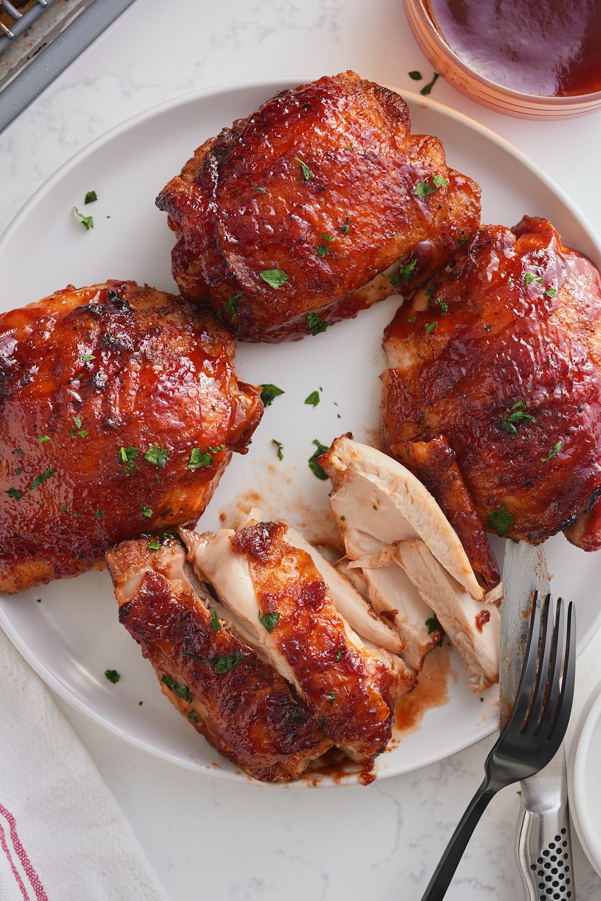 baked bbq chicken thighs being eaten from a plate.