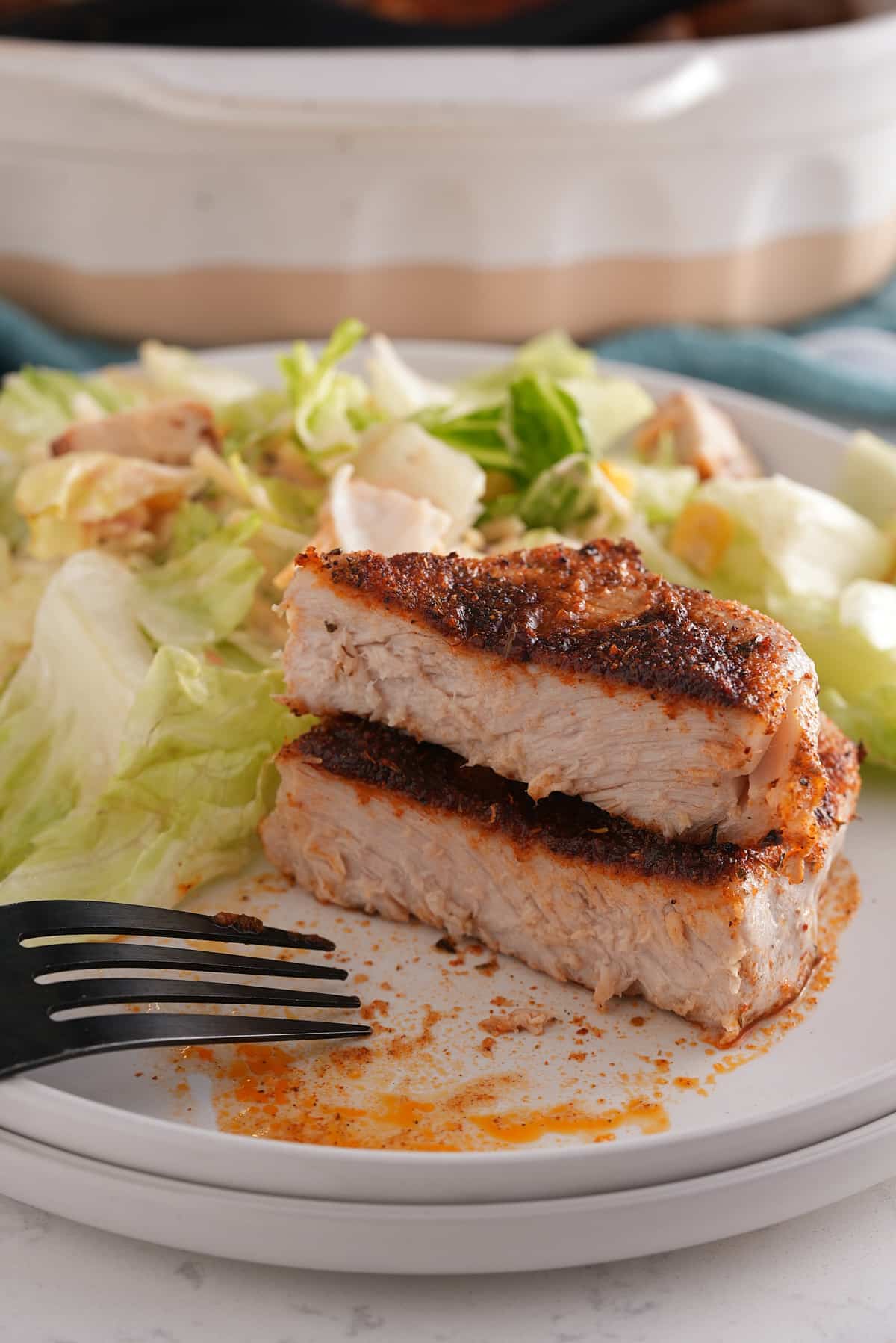 A baked pork chop cut in half on a plate.