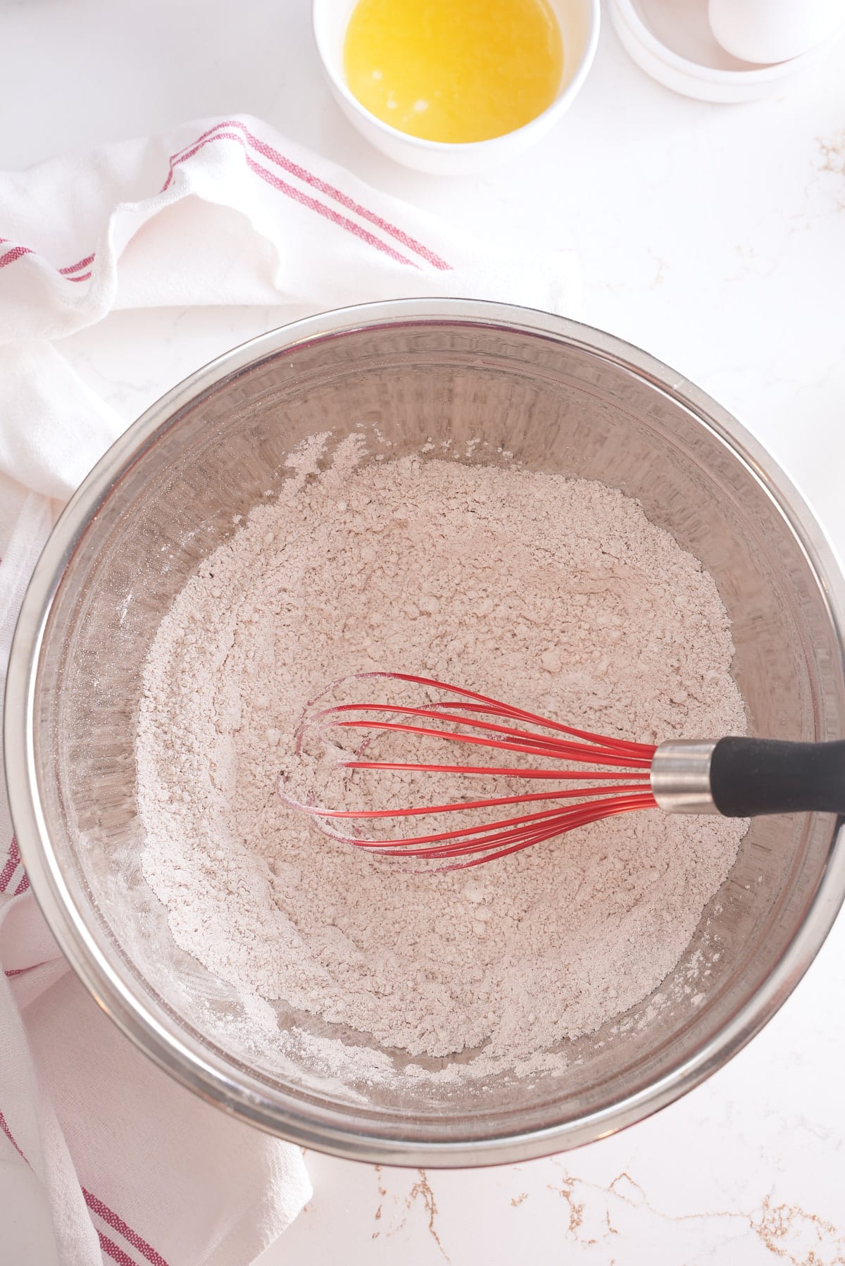 A whisk and bowl of combines flour, baking powder, spice and salt.