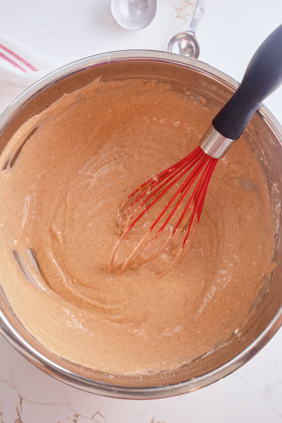A whisk and bowl of sweet potato waffle batter.