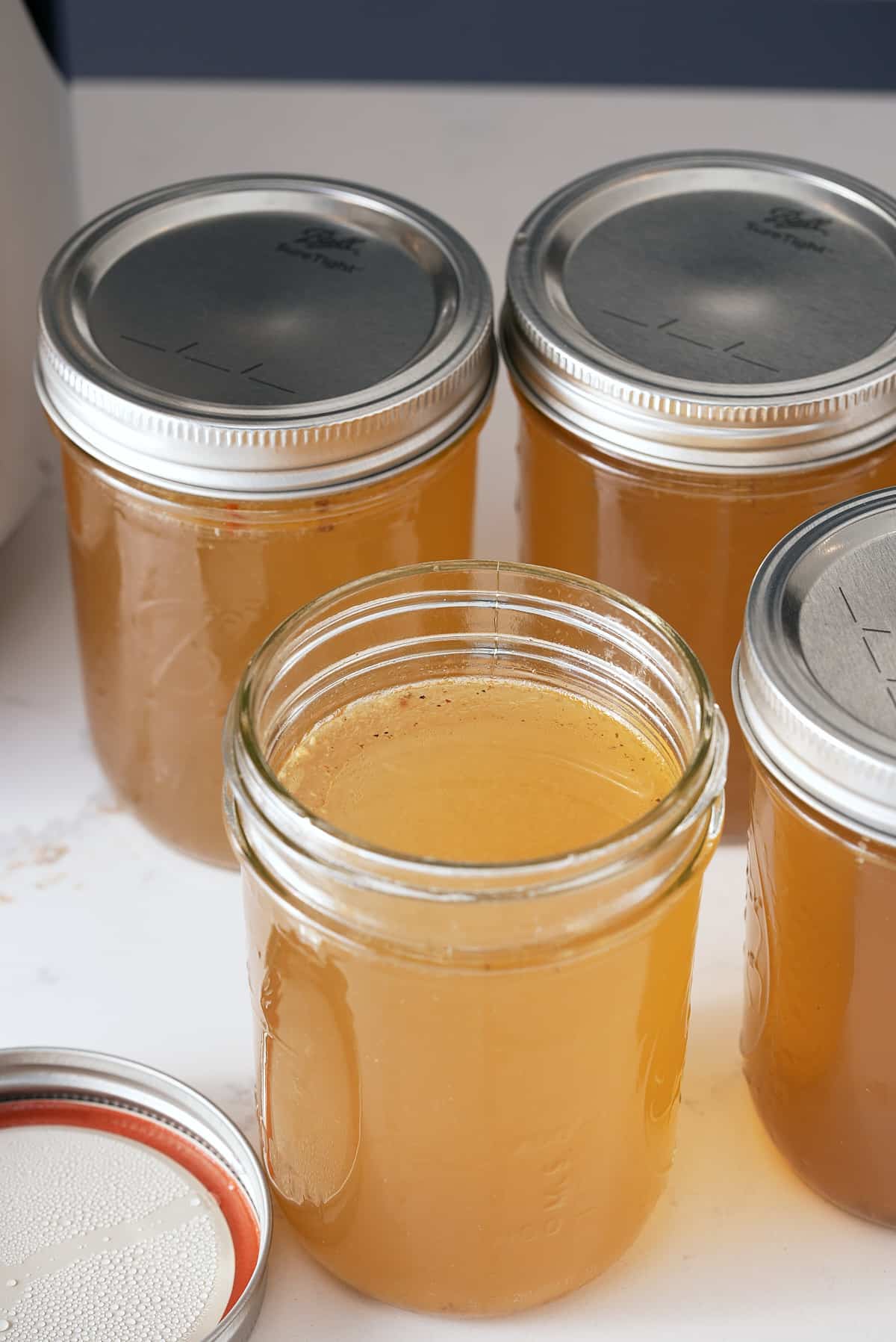 Four jars of cooked and cooled turkey stock.