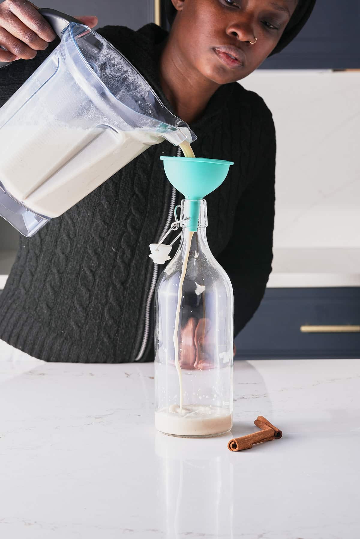 Pouring the coquito cocktail into a serving jar from the blender.