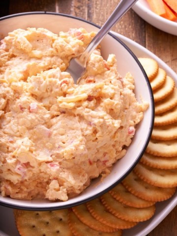 Pimento cheese served in a bowl next to crackers.