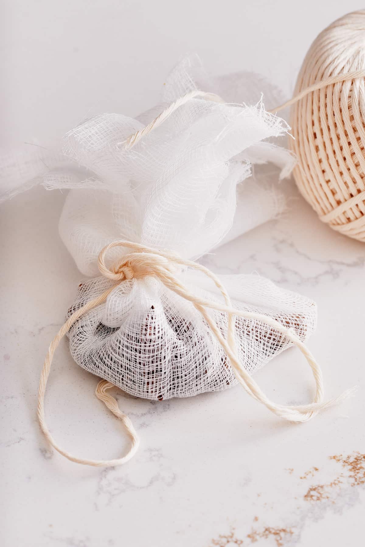 A cheesecloth sachet tied with string and filled with whole spices.