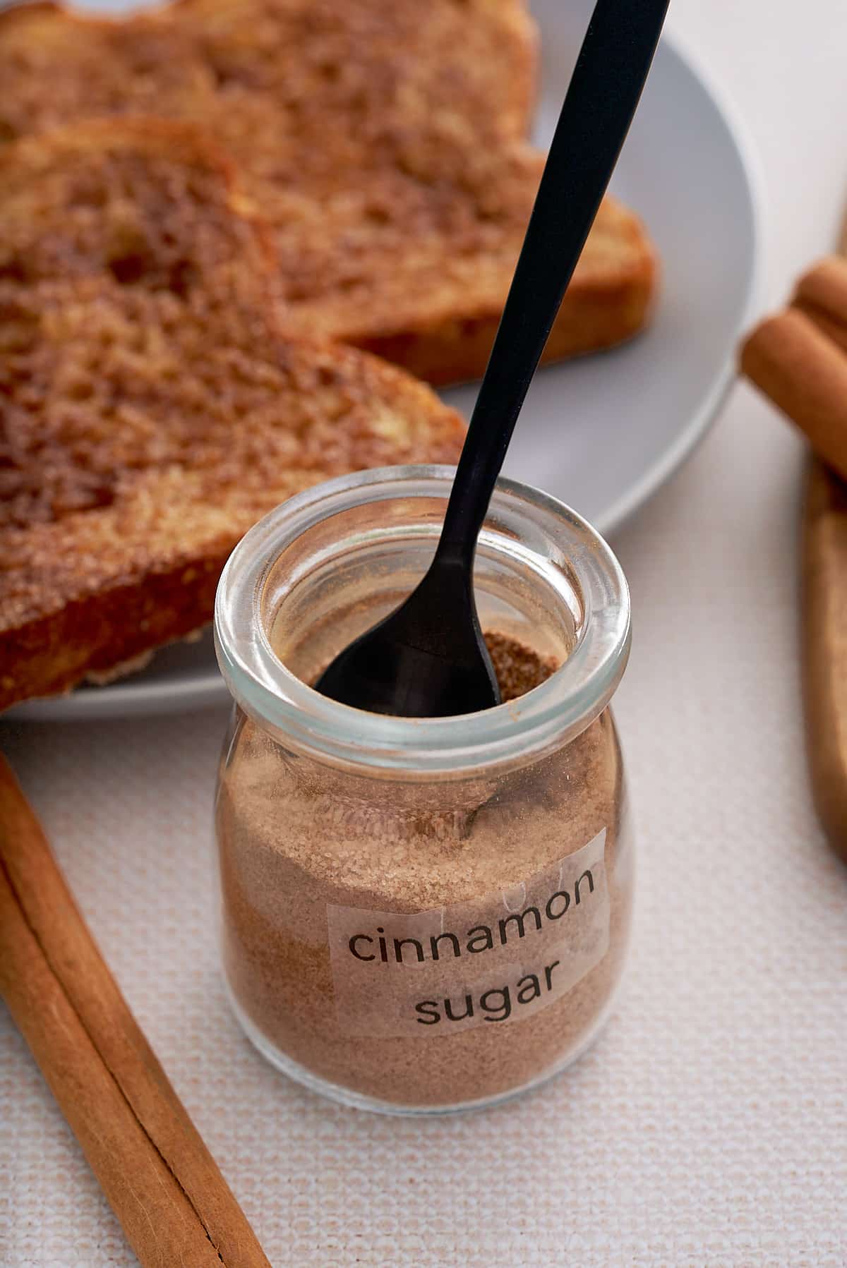 A labeled jar of cinnamon sugar with cinnamon toast set alongside.