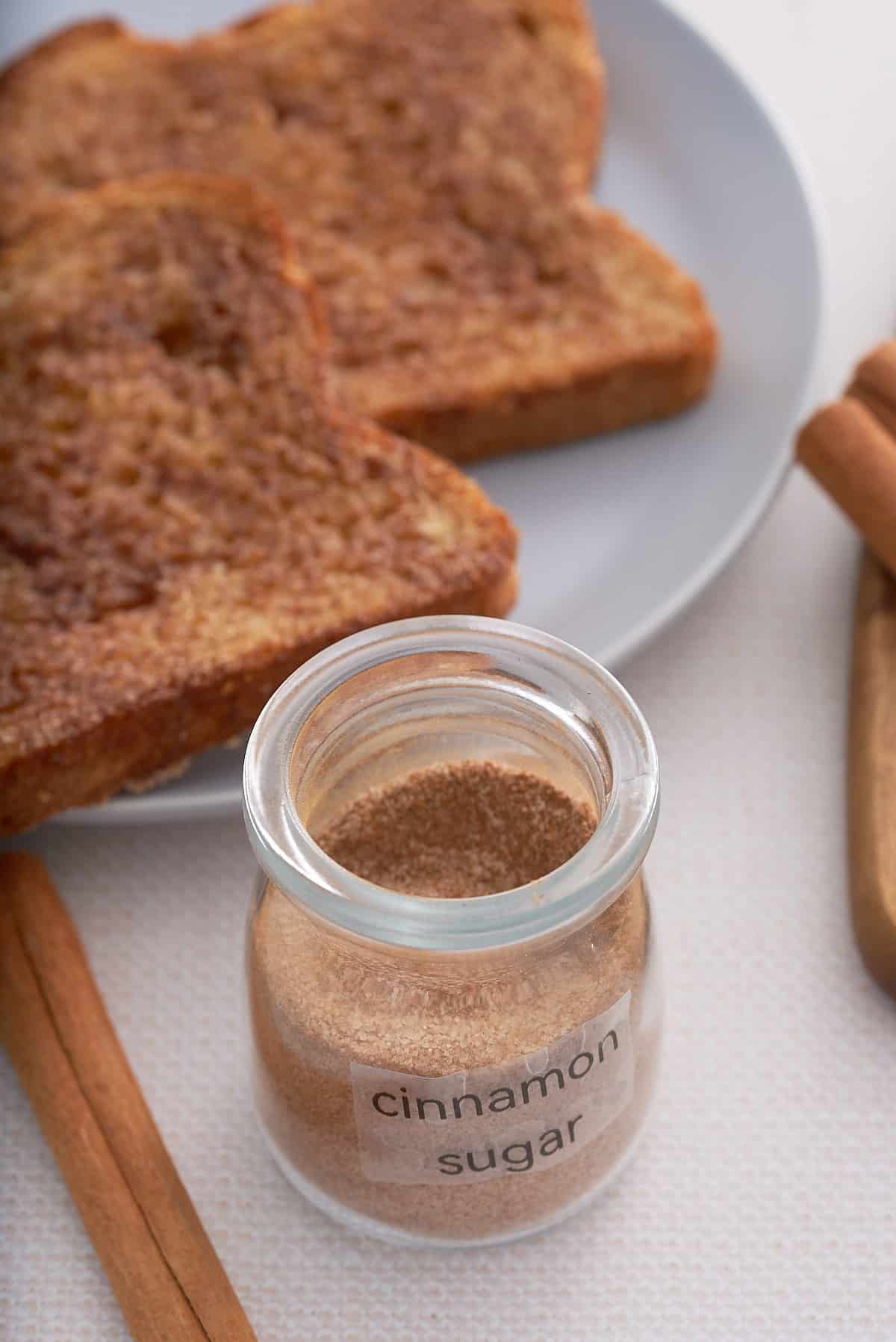 A labeled jar of cinnamon sugar with cinnamon toast set alongside.