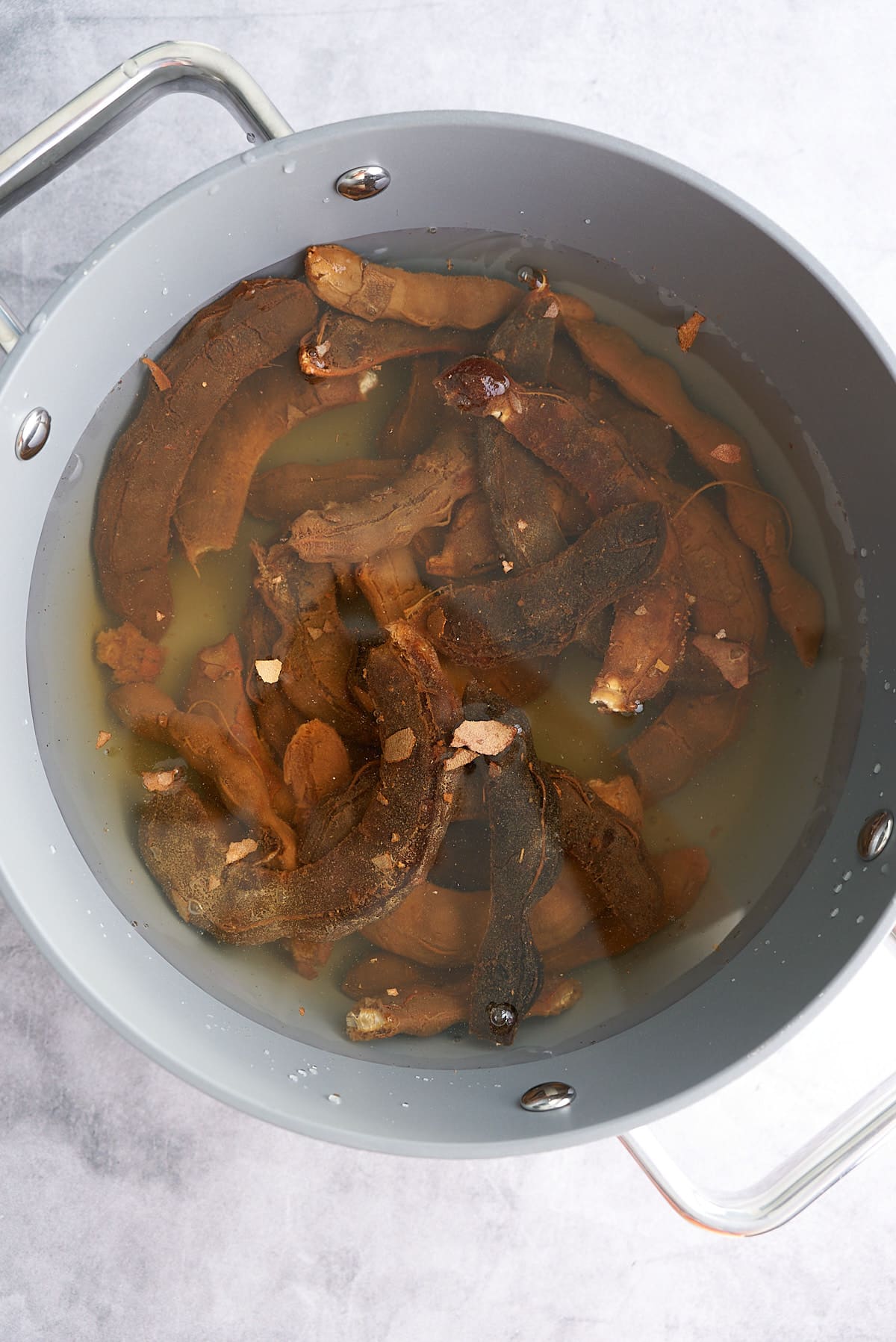 A large pot filled with tamarind pods and water.