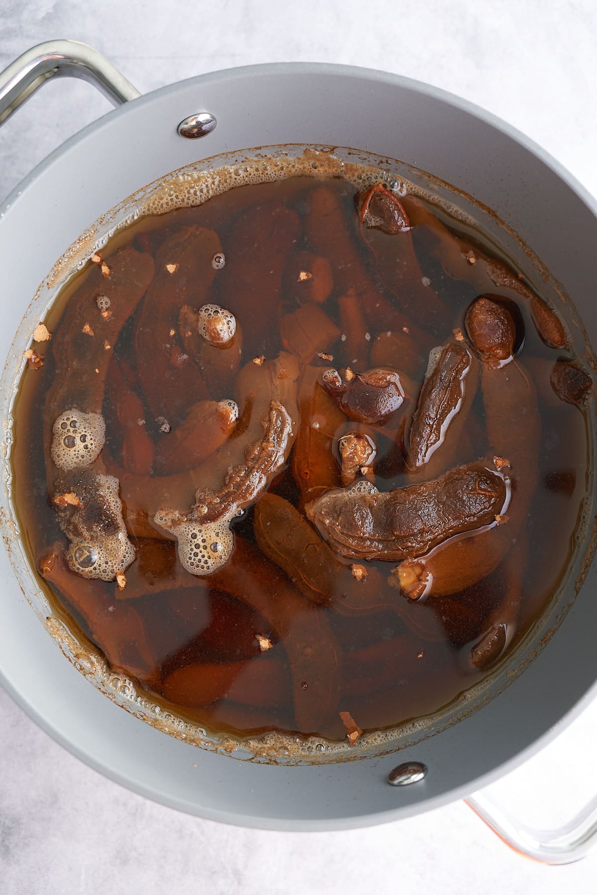 A large pot of cooked tamarind pods and water.