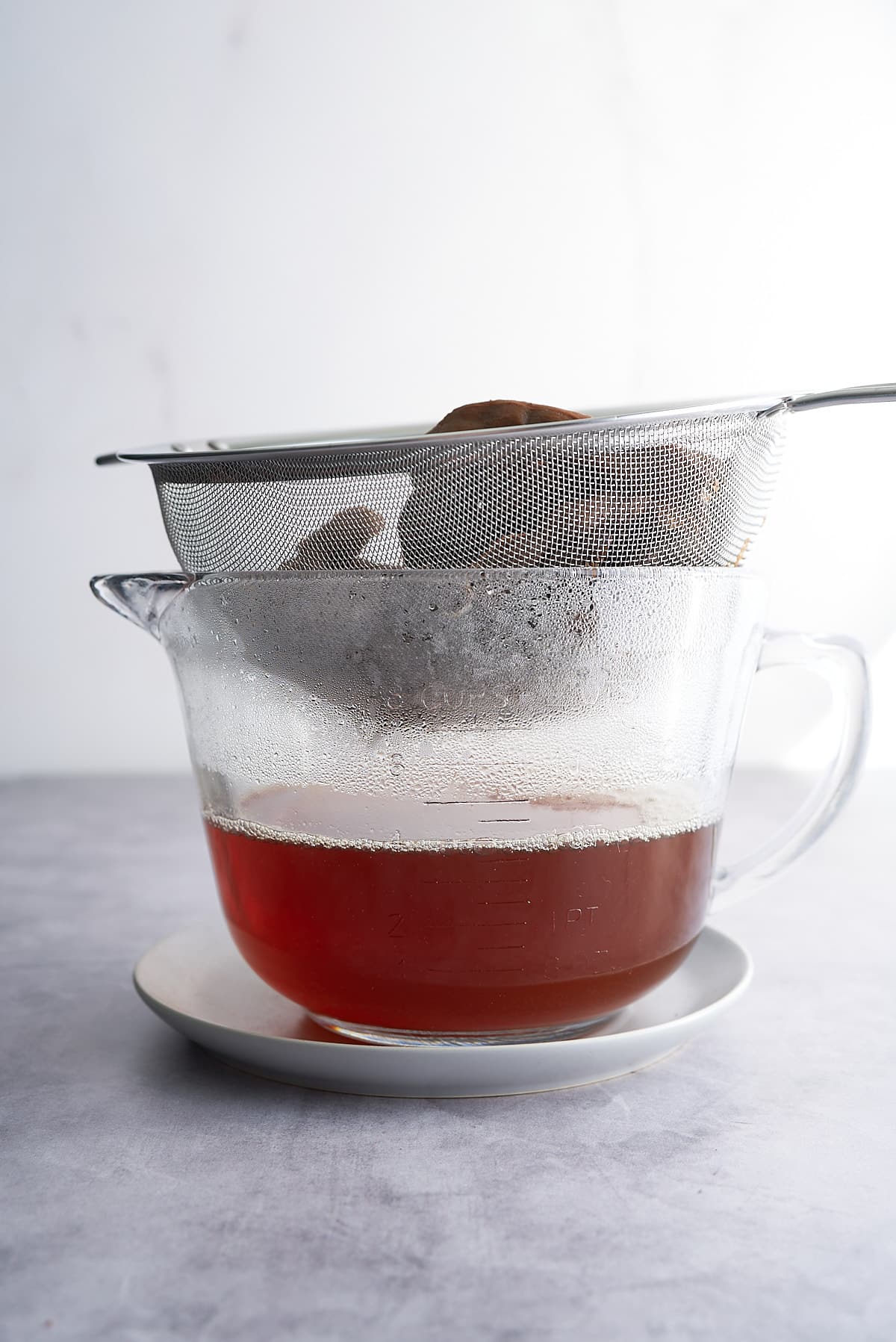 A sieve of tamarind and water, placed over a glass jug.