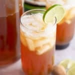 Two glasses of iced tamarind juice garnished with a slice of fresh lime.