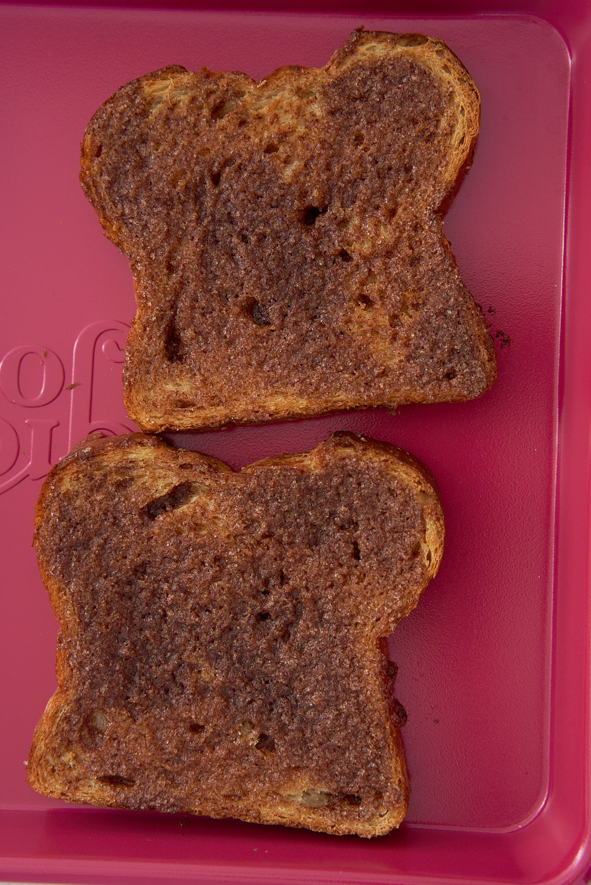 A tray with 2 slices of toasted whole wheat bread topped with cinnamon sugar butter.
