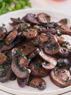 A white plate piled high with sauteed mushrooms.
