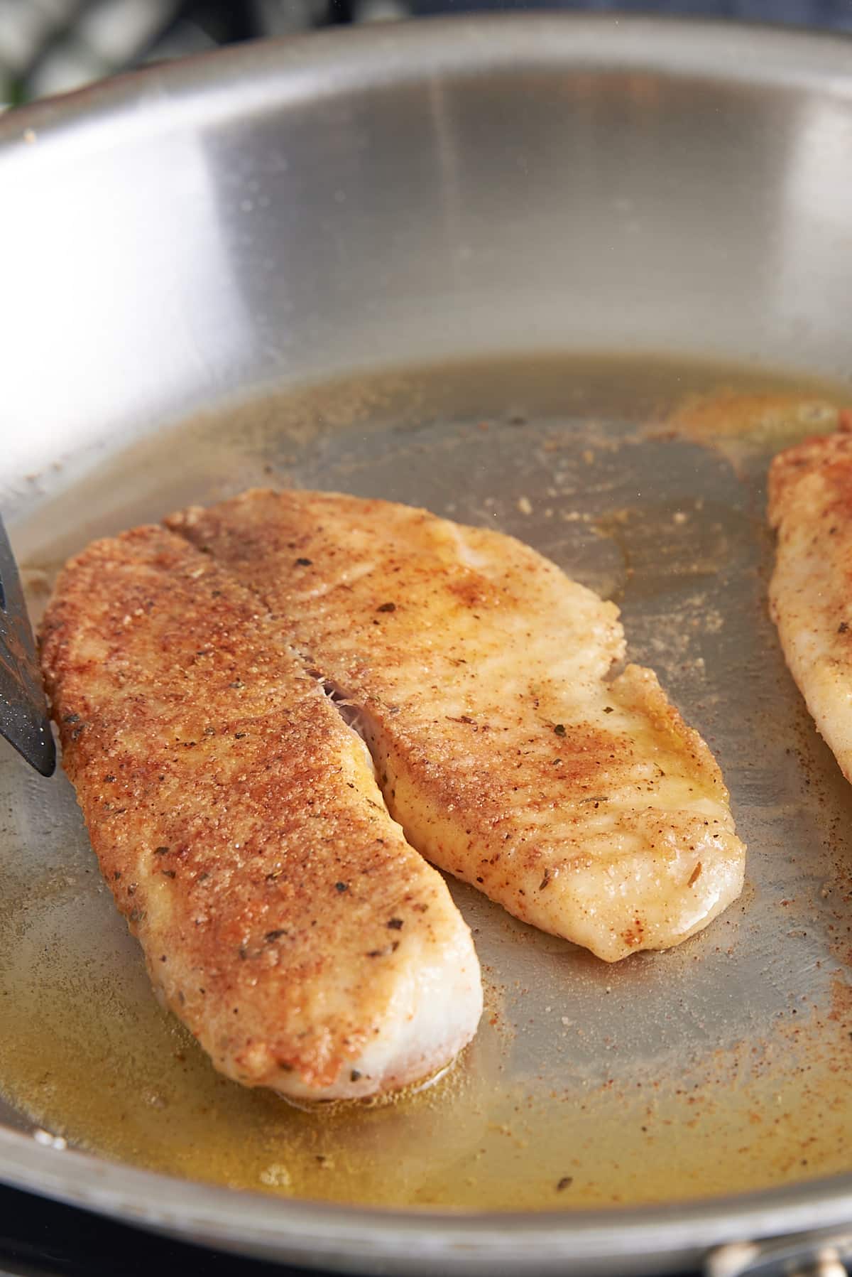 2 sauteed white fish filets in a large skillet.